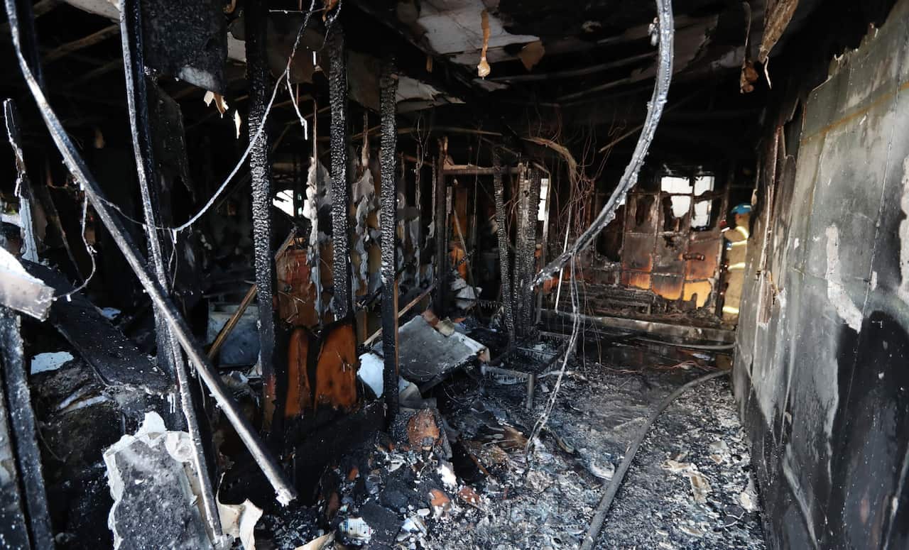 A firefighter inspects a burnt hospital after a fire in Miryang, South Korea, Friday, Jan. 26, 2018 (AAP)