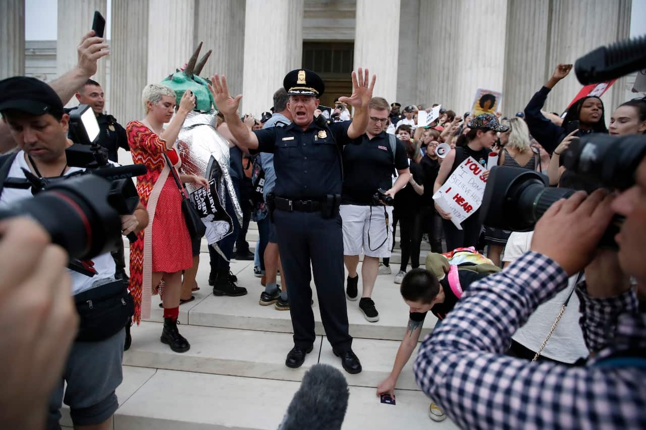 Police move activists as they protest on the steps of the Supreme Court after the confirmation