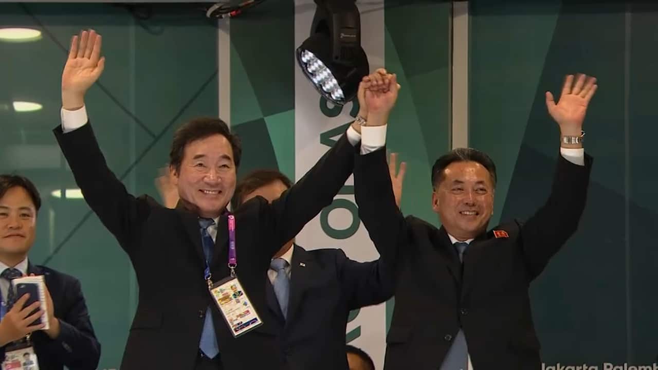 South Korean Prime Minister Lee Nak-yon (left) and North Korean Deputy Prime Minister Ri Ryong Nam (right) waving while holding hands.