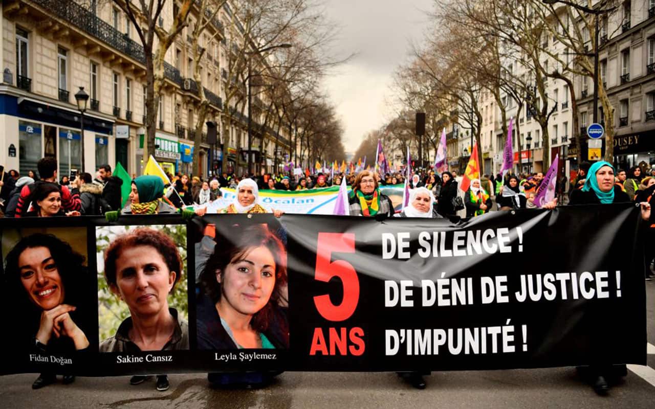 People hold a banner with the portrait of the three Kurdish activists during a demonstration in Paris on January 6, 2018.