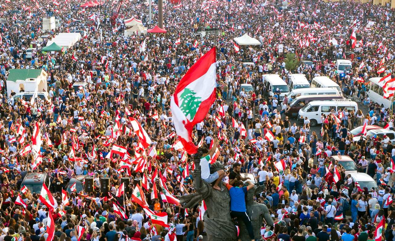 Protesters wave Lebanese flags and shout anti-government slogans during a protest in front of Muhammad al-Amin Mosque in downtown Beirut.