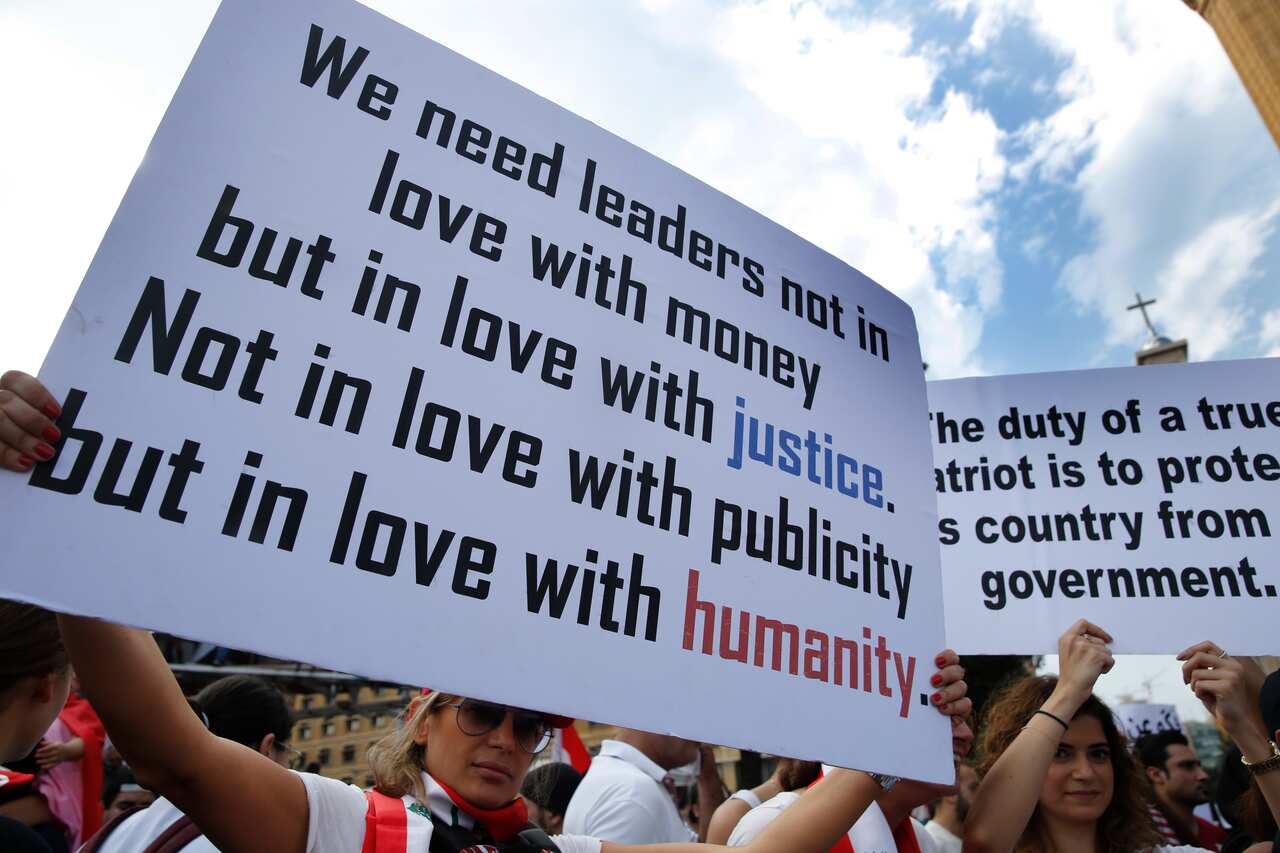 Anti-government protesters hold placards as they protest, in downtown Beirut.