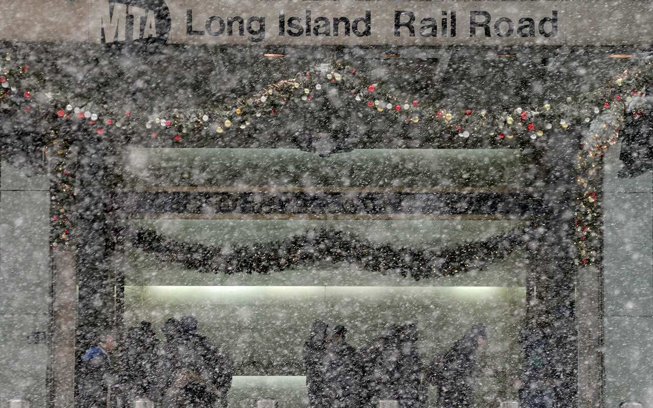 Pedestrians standing at the entrance of the Long Island Railroad are obscured by snow in New York, Thursday, Jan. 4, 2018. 