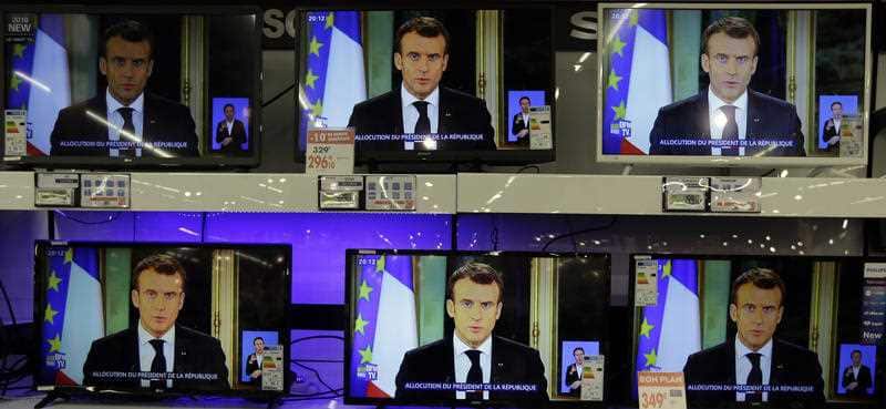 TV screens show French President Emmanuel Macron during a televised address to the nation.