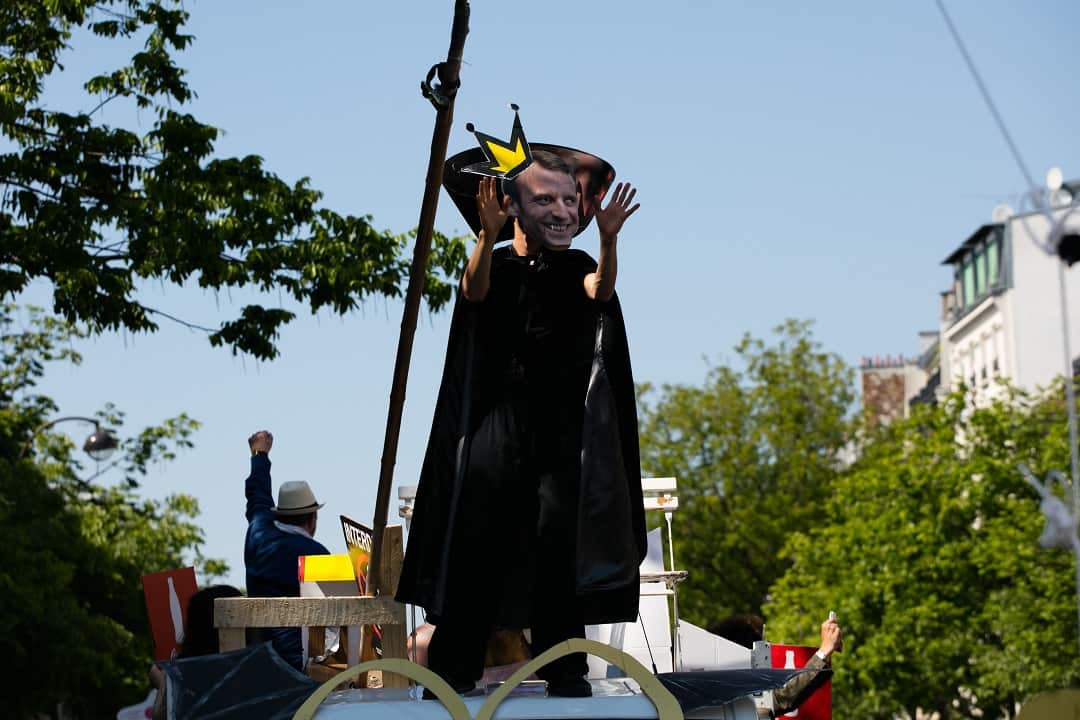 A protester wears a mask depicting the French President Emmanuel Macron as a king.