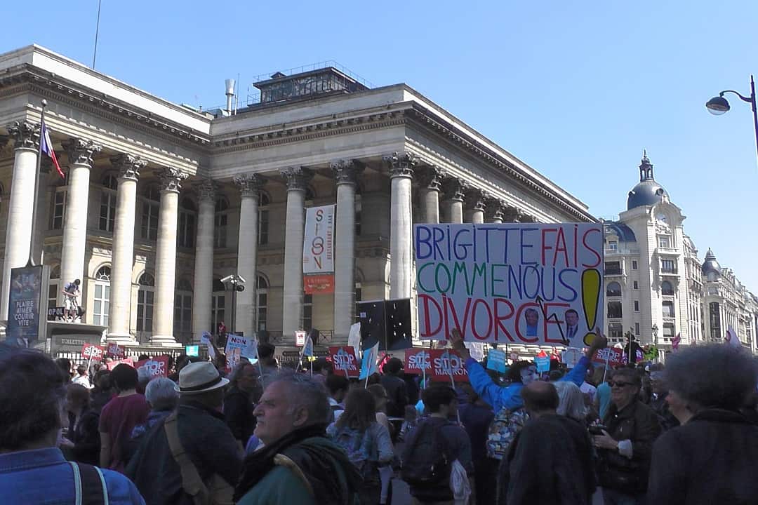 A protester holds a sign reading "Brigitte do just like us, get a divorce".