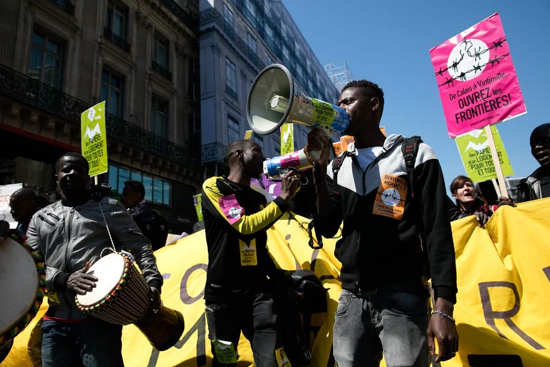 Protesters shout slogans as thousands march in "The party for Macron" (La Fete a Macron) rally.