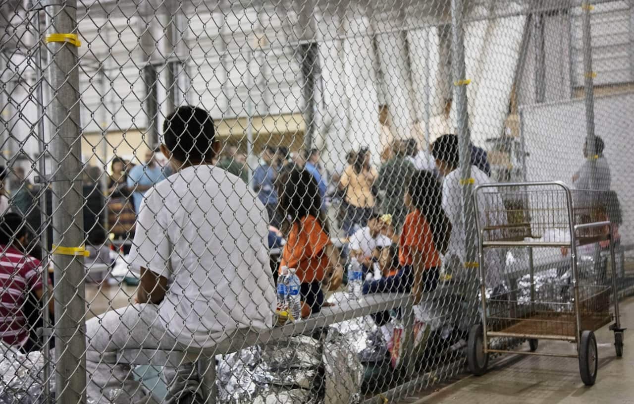 people who've been taken into custody related to cases of illegal entry into the United States, sit in one of the cages at a facility in McAllen