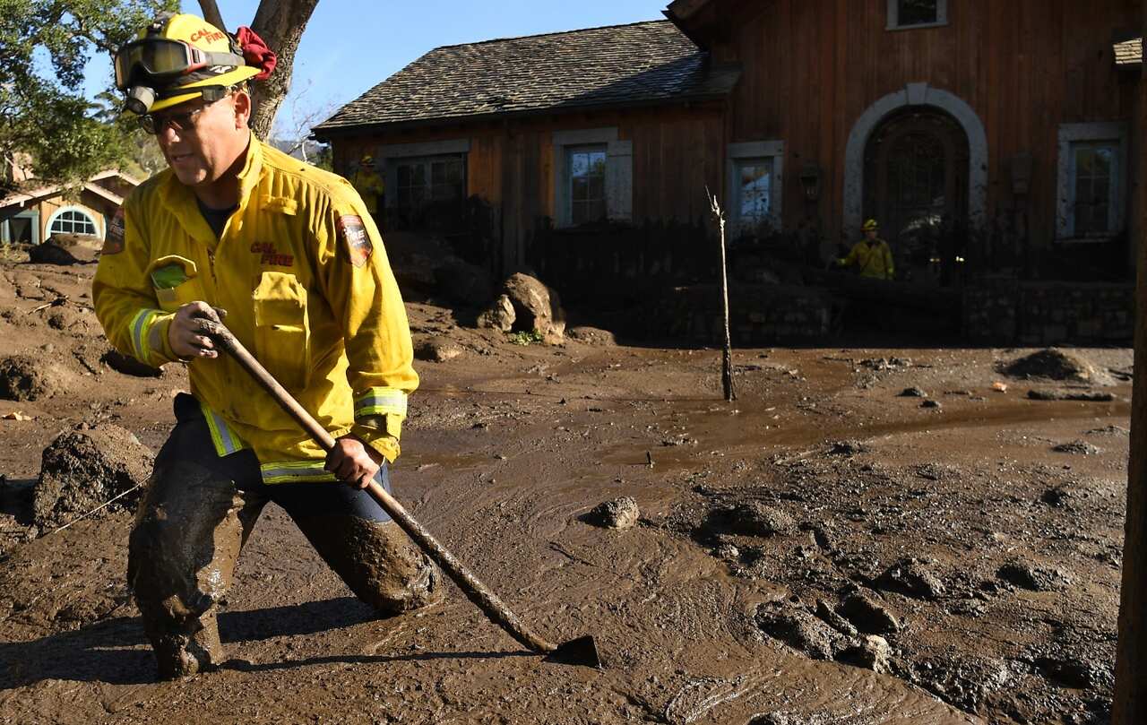 Cal Firefighter Alex Jimenez walks out after marking a spot with a stick where he found a body under the mud at a house along Glen Oaks Drive