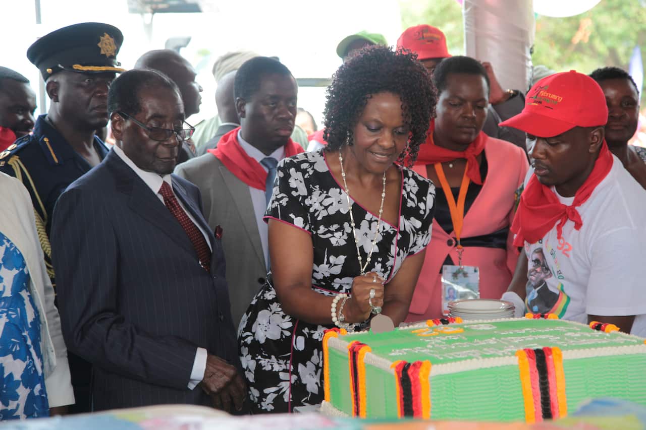 Zimbabwean President Robert Mugabe, left, watches as his wife Grace cut one of his birthday cakes