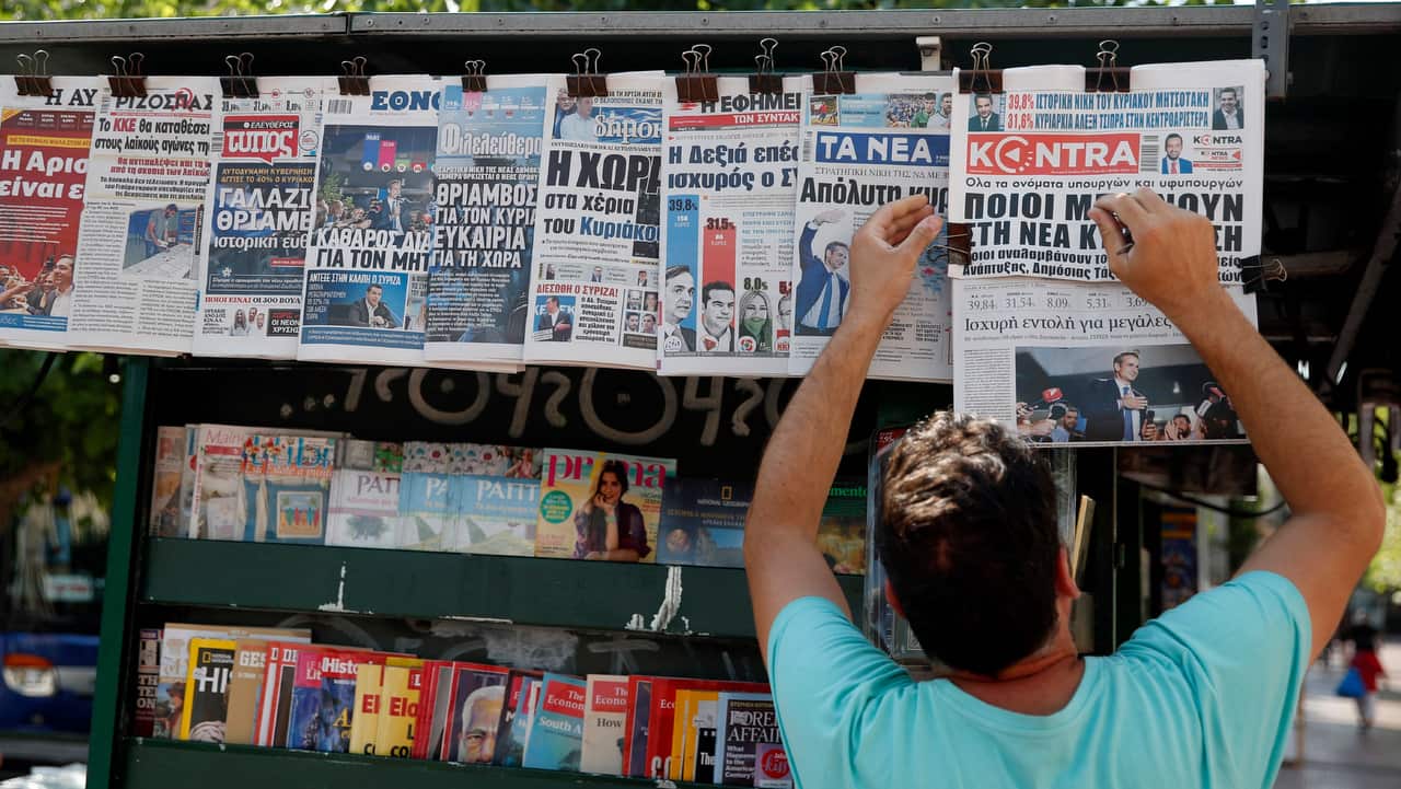 A vendor adjusts the front pages of the Greek newspapers as all of them refer to the election result in Athens.