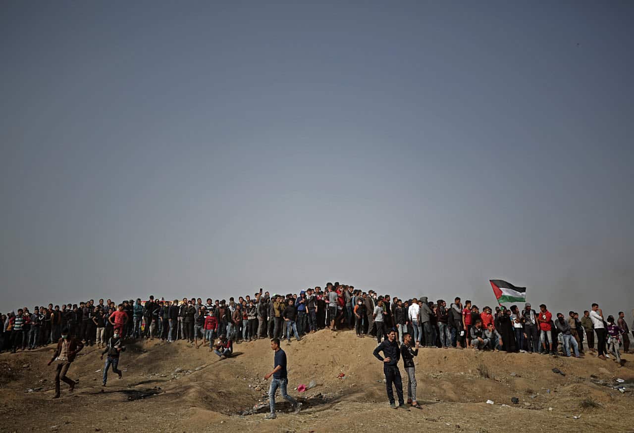 Palestinians gather during clashes with Israeli troops near the border with Israel in the east of Gaza City on, 13 April 2018 