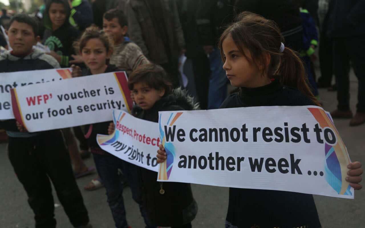Palestinian children hold banners against cutting off food aid during the protest outside the UN headquarters in Gaza City, January 4, 2018.