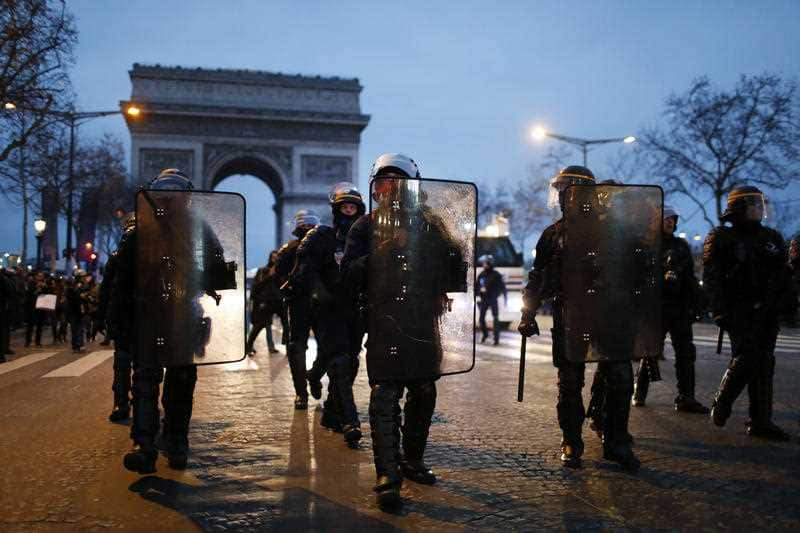 Riot police march towards gathered Yellow Vest protesters in Paris.