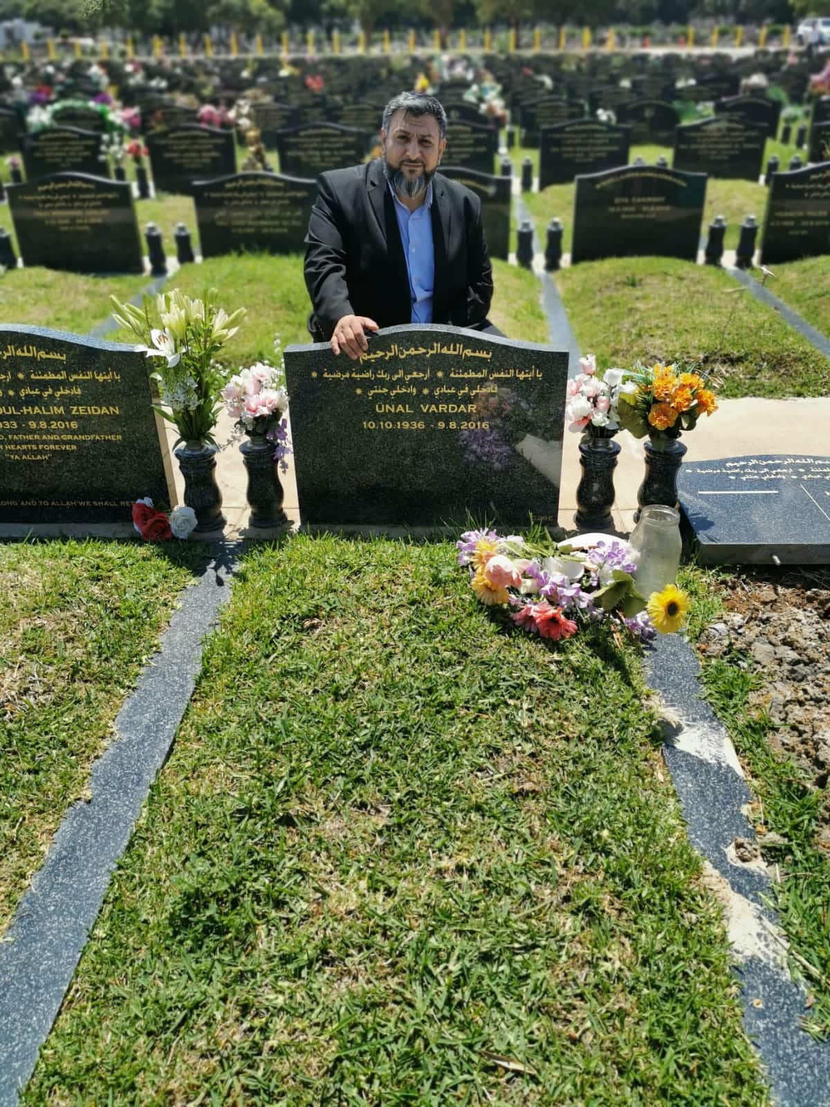 Davud sitting near a grave stone at a cemetery.