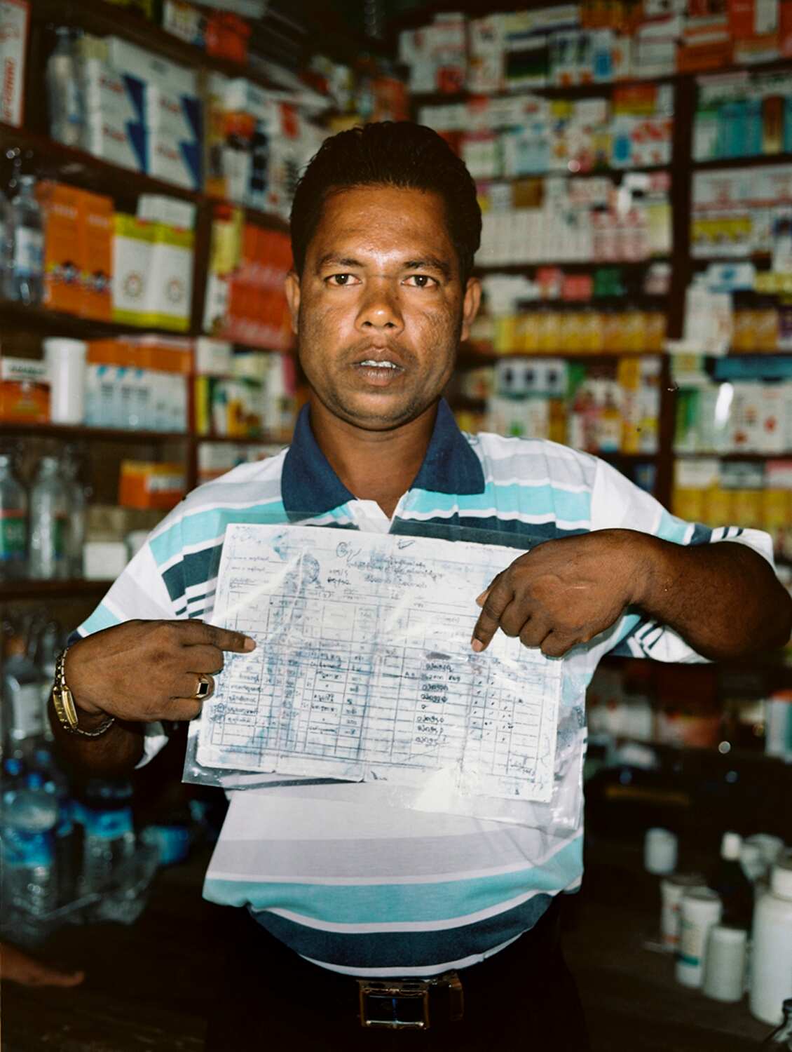 A man showing Myanmar government papers identifying him as a Rohingya.