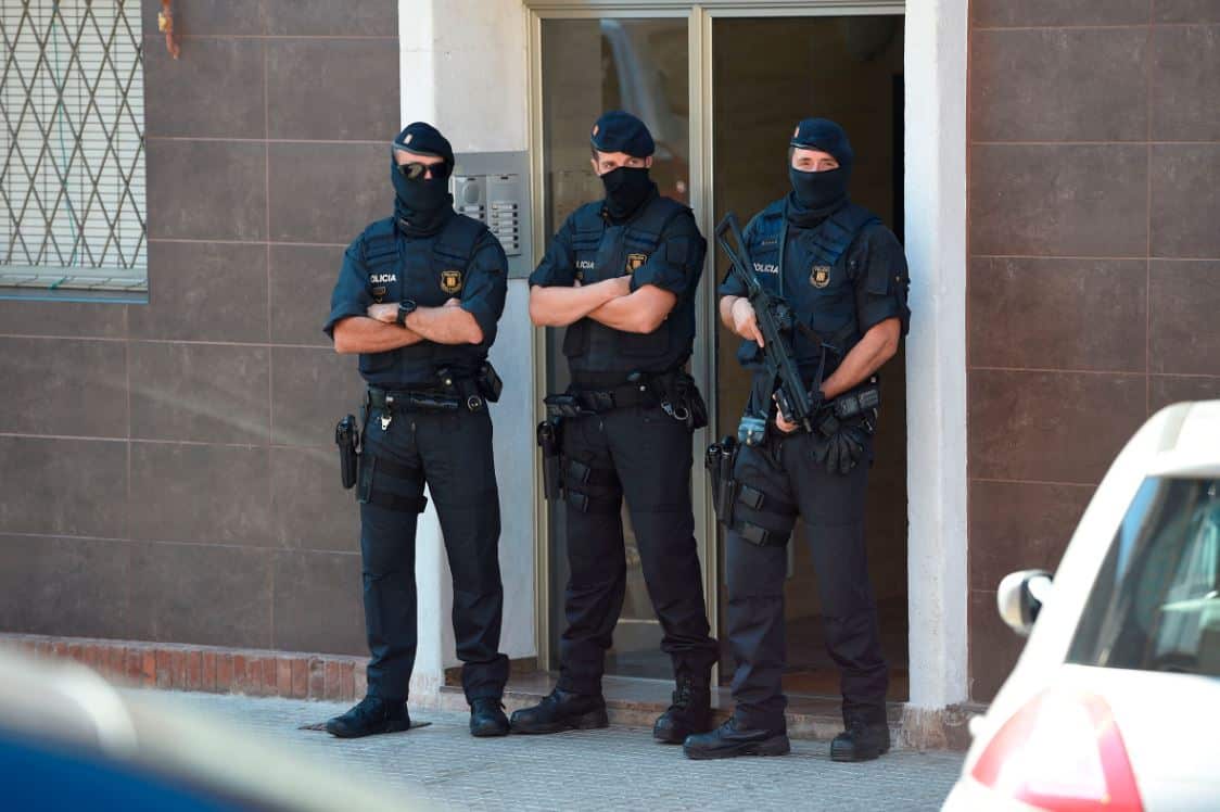 Catalan regional police stand guard outside the apartment building of a man who tried to attack a police station in Cornella.
