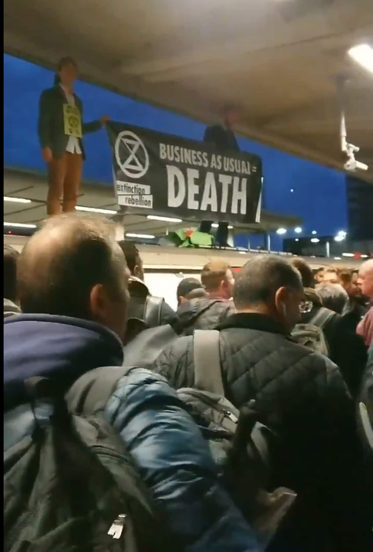 Extinction Rebellion protesters on the roof of an underground train surrounded by angry commuters at Canning Town station in east London.