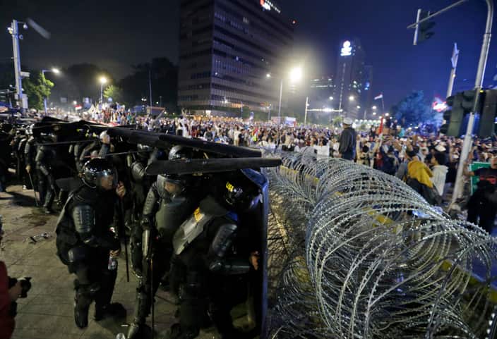 Riot police officers take defensive position during clashes with supporters of Indonesian presidential candidate Prabowo Subianto in Jakarta.