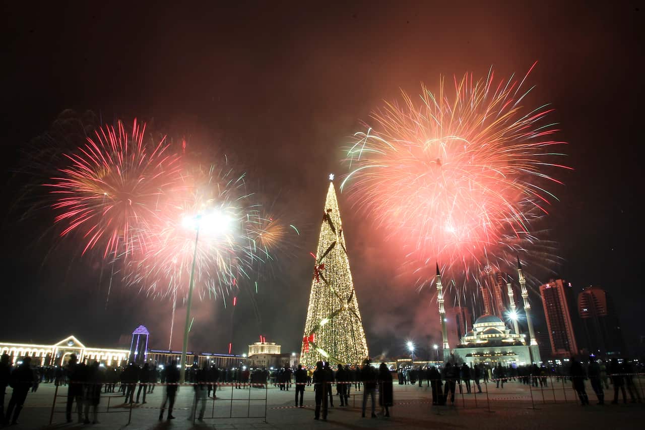 Fireworks explode over a not-too-crowded square with a Christmas tree and skyscrapers during New Year's celebrations in Grozny, Russia.