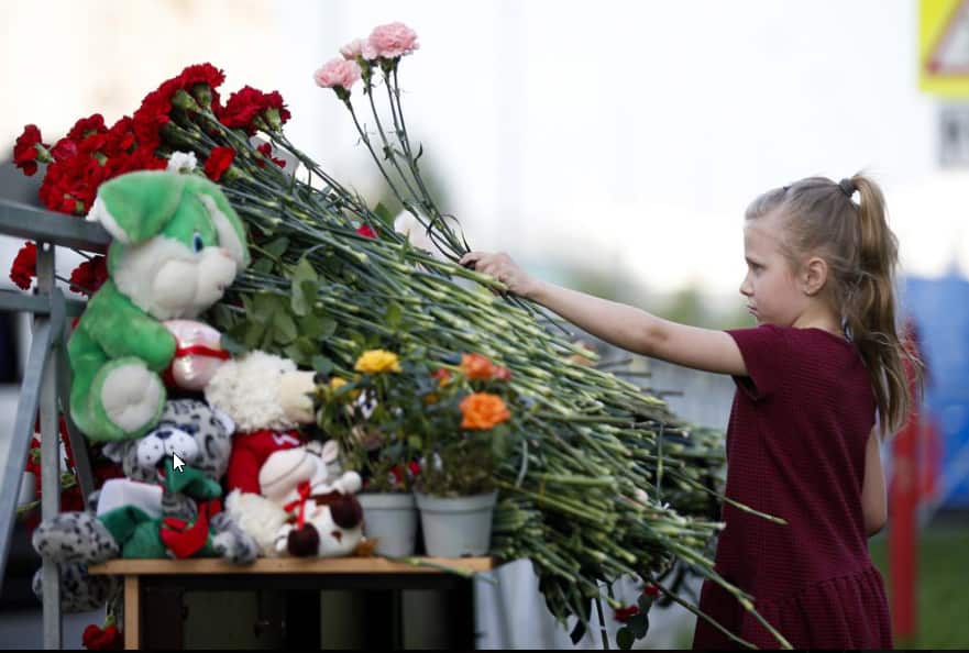 A girl lays flowers near a school after a shooting in Kazan, Russia, Tuesday, May 11, 2021. Russian officials say a gunman attacked a school in the city of Kazan and Russian officials say several people have been killed.
