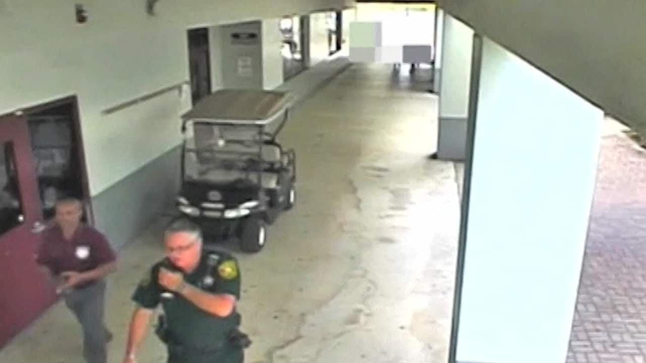 Feb 14 2018: Deputy Scot Peterson, right, leaving the Marjory Stoneman Douglas High School after standing at the front door.