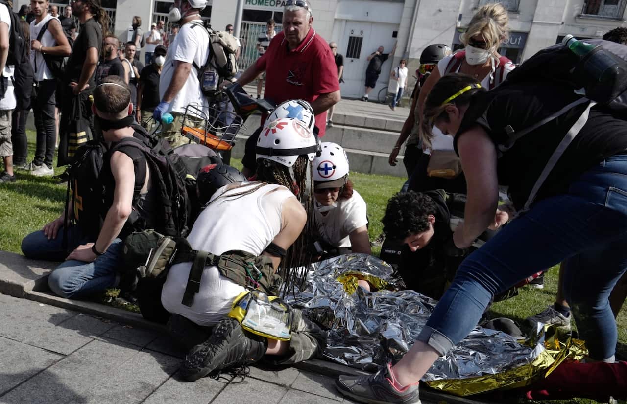 Street medics give assistance to a person before being evacuated to hospital by firefighters.
