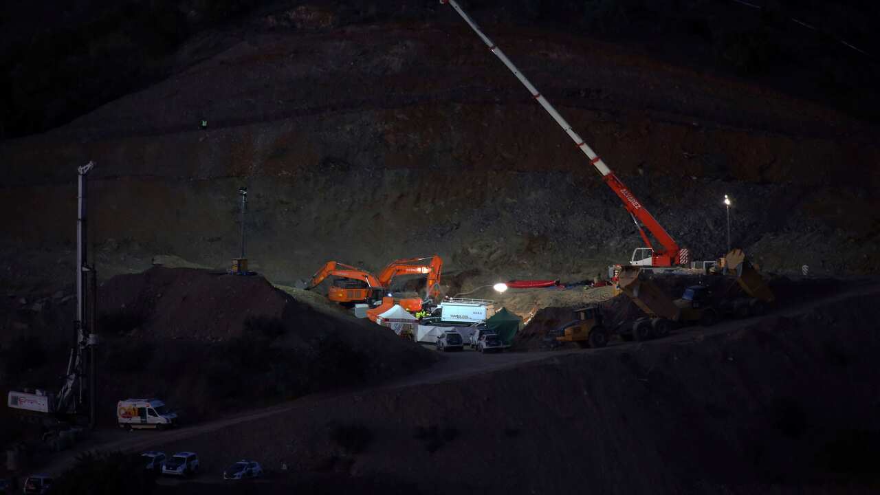 Drill and excavating machinery work on top of the mountain next to a deep borehole to reach the trapped boy.