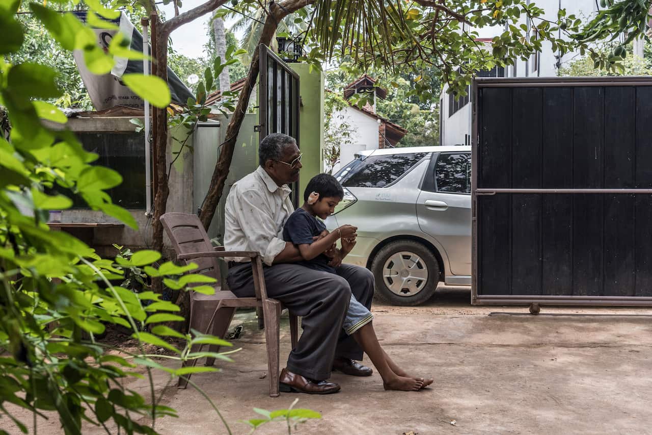 Gavin Silva, who was wounded in the Easter Sunday bombing at St. Sebastian's Church, sits on a relative's lap at his family home in Negombo, Sri Lanka.