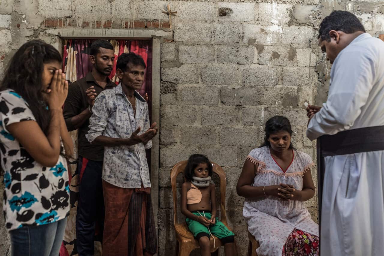 Biguni, who was wounded in the Easter Sunday bombing at St. Sebastians Church, waits to receive communion with relatives at their family home in Negombo, Sri Lanka.