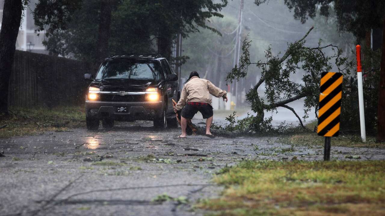 A man moves a large tree limb that downed power lines in North Myrtle Beach's Cherry Grove community.  