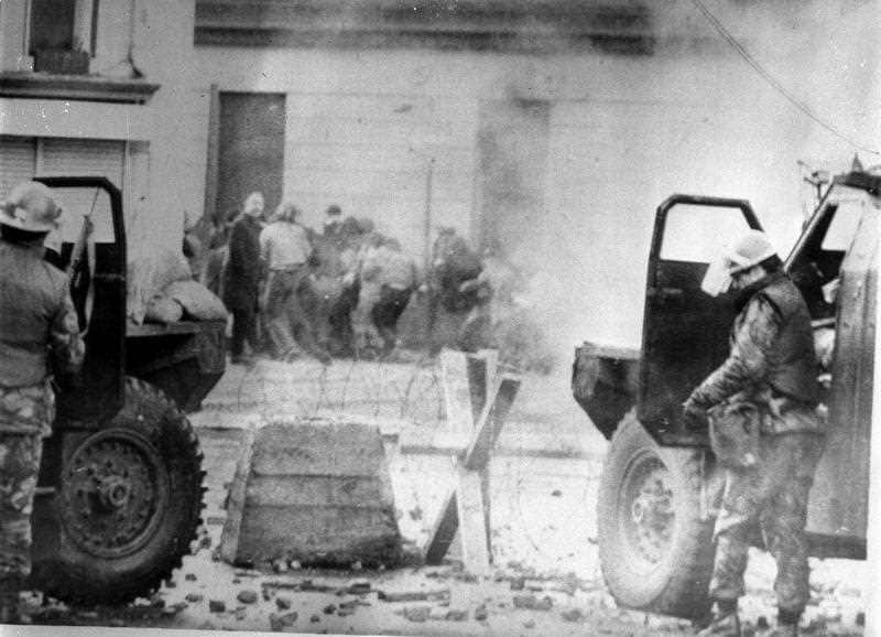 Soldiers take cover behind their sandbagged and armoured cars while dispersing rioters with CS gas during the Bloody Sunday riots.
