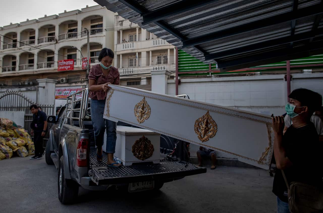Morgue staff carry in coffins for the victims. Thai officials say a soldier who went on a shooting spree and killed numerous people inside a mall in Thailand.