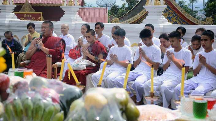The Thai cave boys offer prayers next to Thai Buddhist monks during a religious worship ritual.