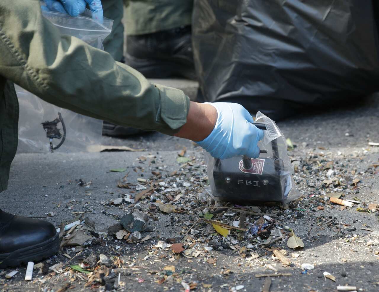 Police use a magnetic tool as they examine debris