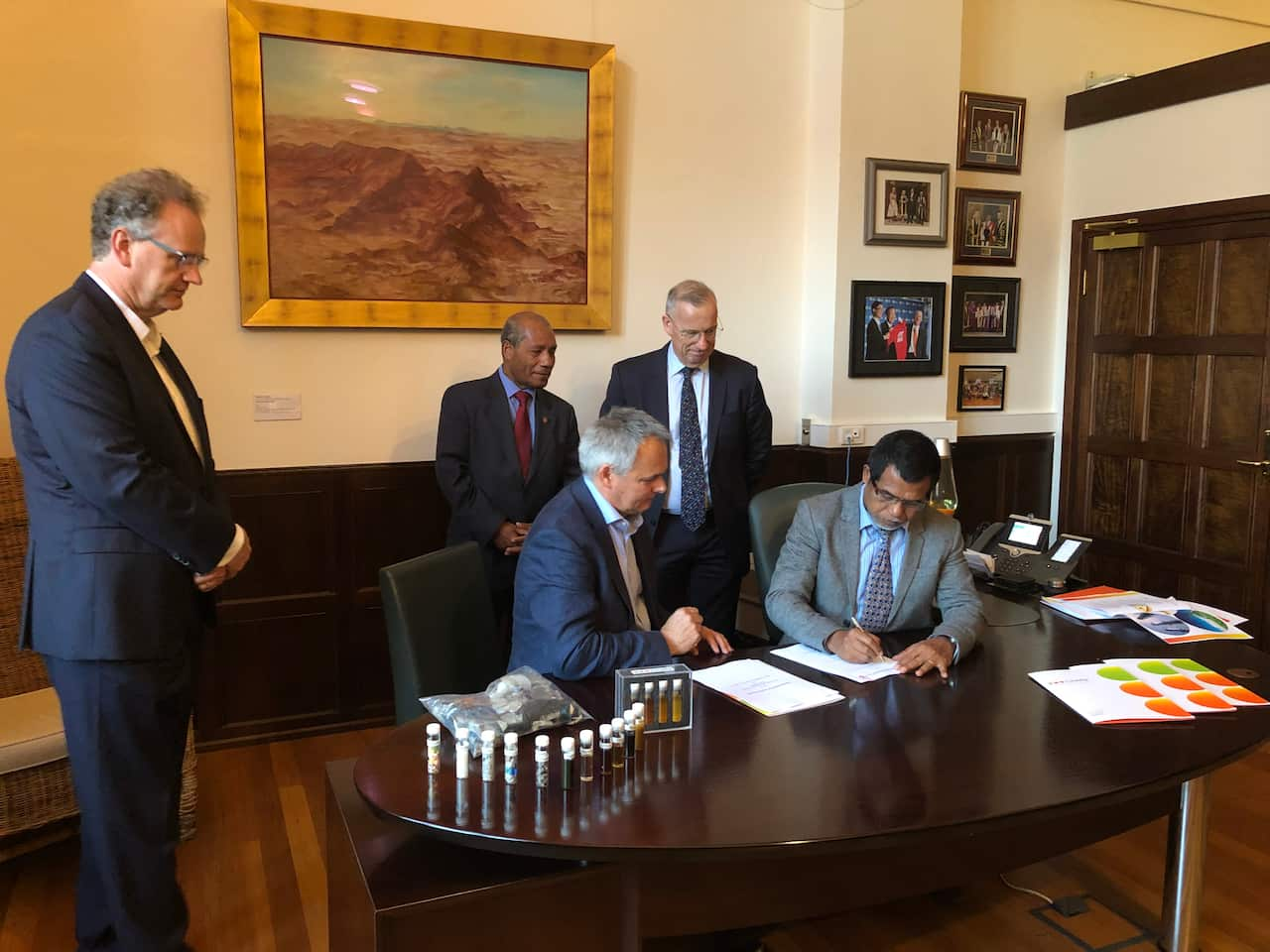 Timor Leste's Secretary of State for the Environment Demetrio do Amaral de Carvalho (standing) and Ambassador Abel Guterres sign the deal at Sydney University.