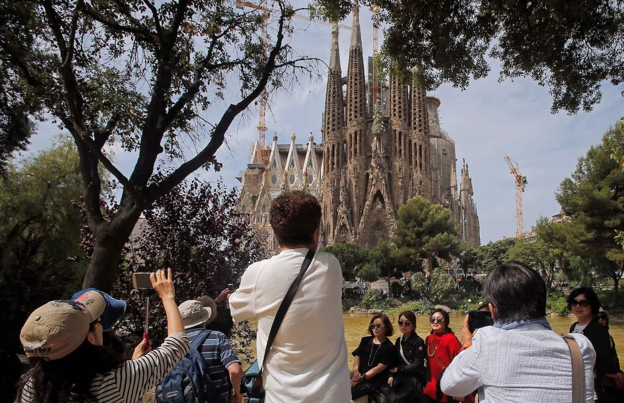 File: Tourists take pictures in front of Sagrada Familia church, designed by architect Antoni Gaudi in Barcelona.