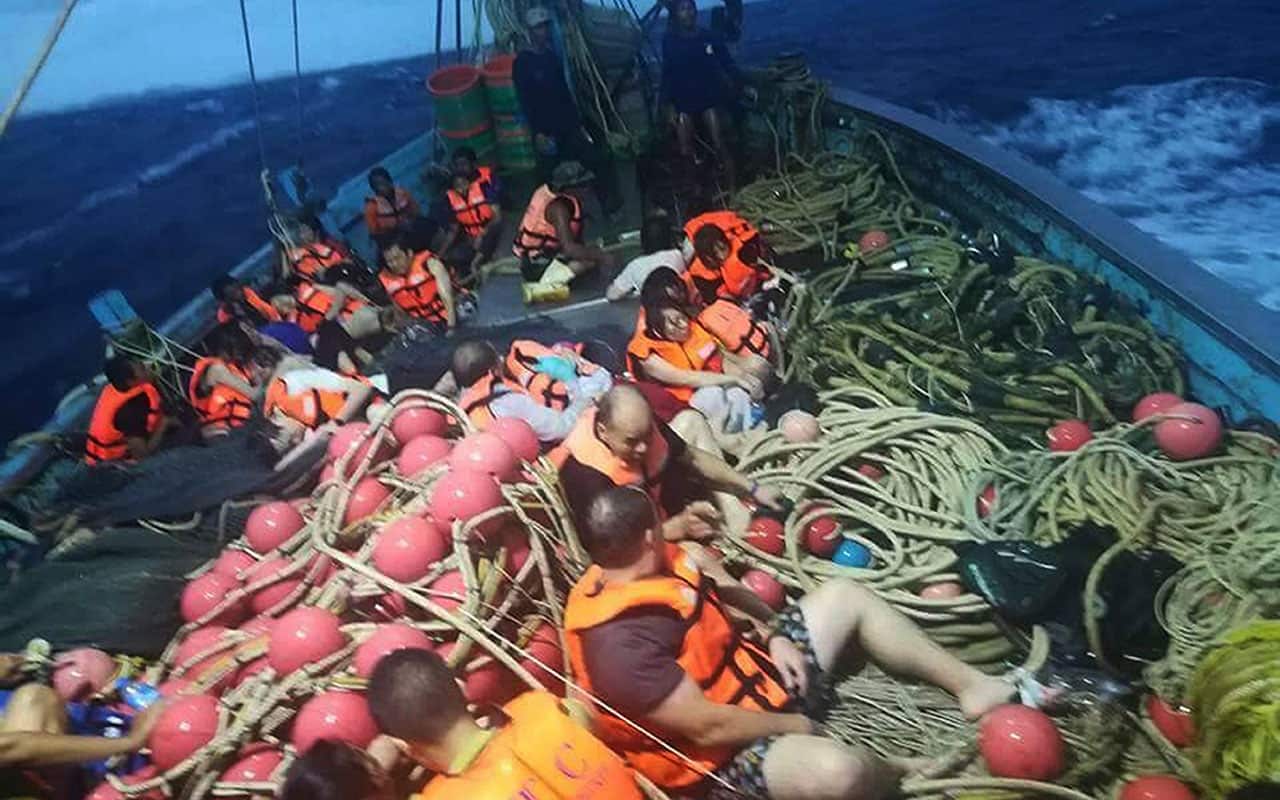 Tourists sitting on a fishing boat after being rescued from the sea near Phuket Island, Thailand.