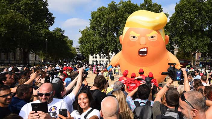 People take a 'selfie' as a 'Baby Trump' balloon rises after being inflated in London's Parliament Square.