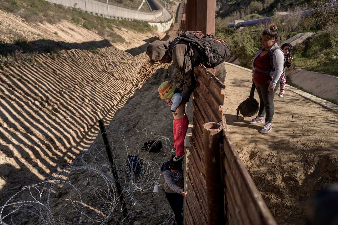 A man passes a Mexican migrant baby to her mother