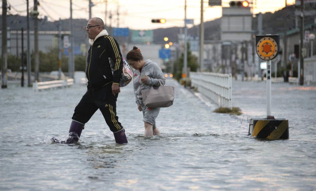 People walk on a water covered street in Ise City, Mie Prefecture on Oct. 23, 2017.