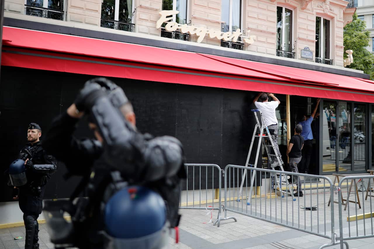 Employees secure the famed Paris restaurant Le Fouquet's on the Champs-Elysees avenue after scuffles with youths after Bastille Day parade.