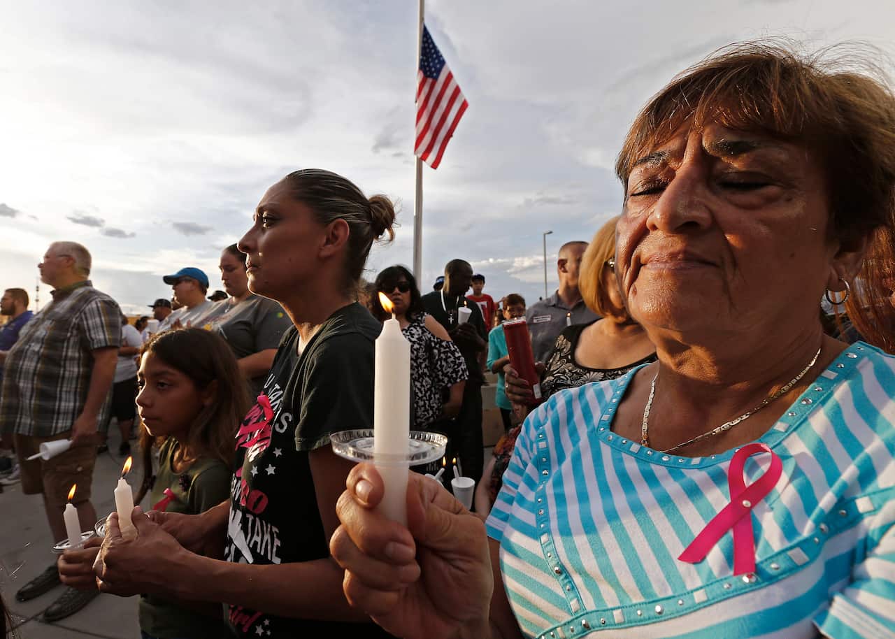 People hold candles at a vigil for victims of the mass shooting. Police say 20 people were killed in what they’re calling “a domestic terrorist case”.