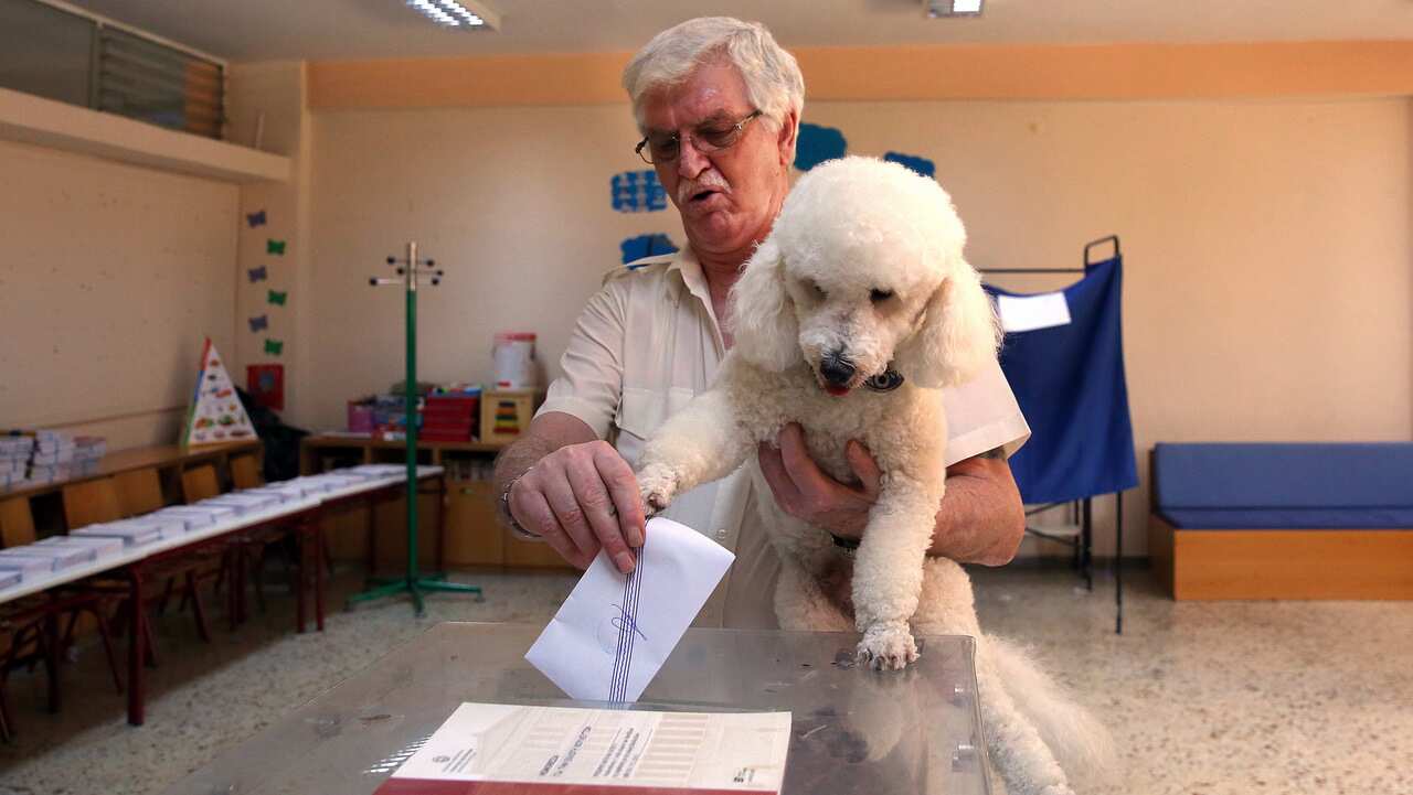 A man, holding his dog, casts his vote during the general elections at a polling station, in Athens.