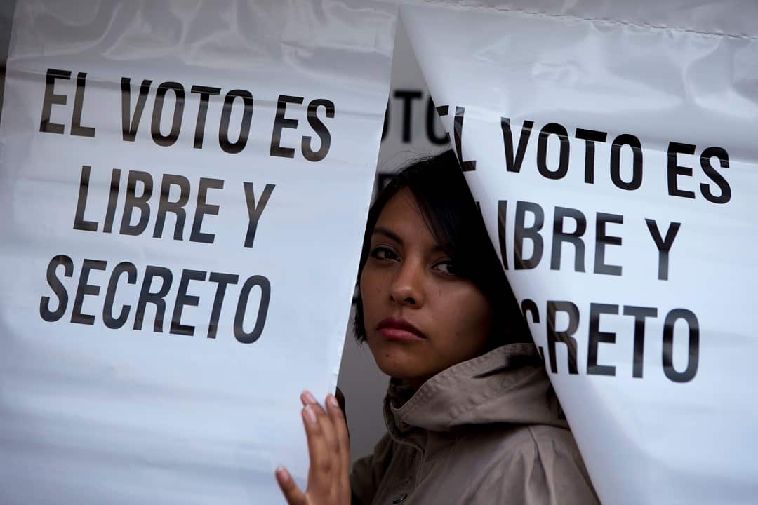 A voter leaves a polling booth that reads "The vote is free and secret". 