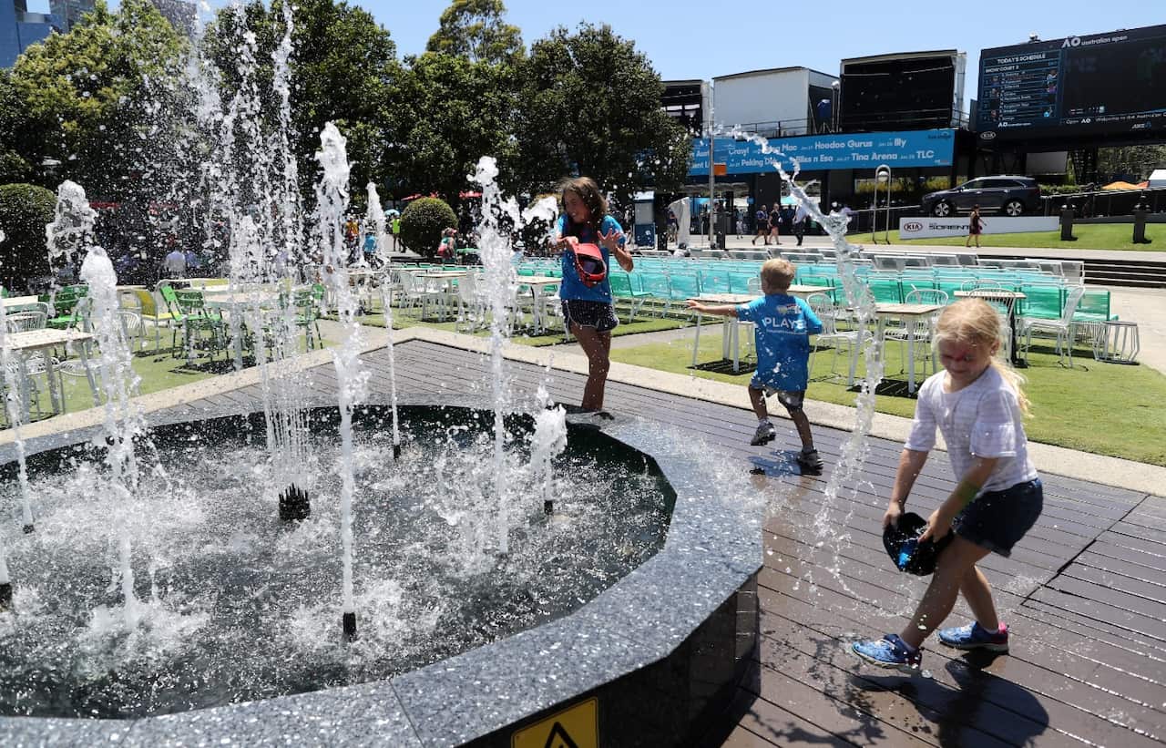 Tennis fans cool down at a water feature on day four of the Australian Open Grand Slam tennis tournament in Melbourne, Australia, 18 January 2018 (AAP)