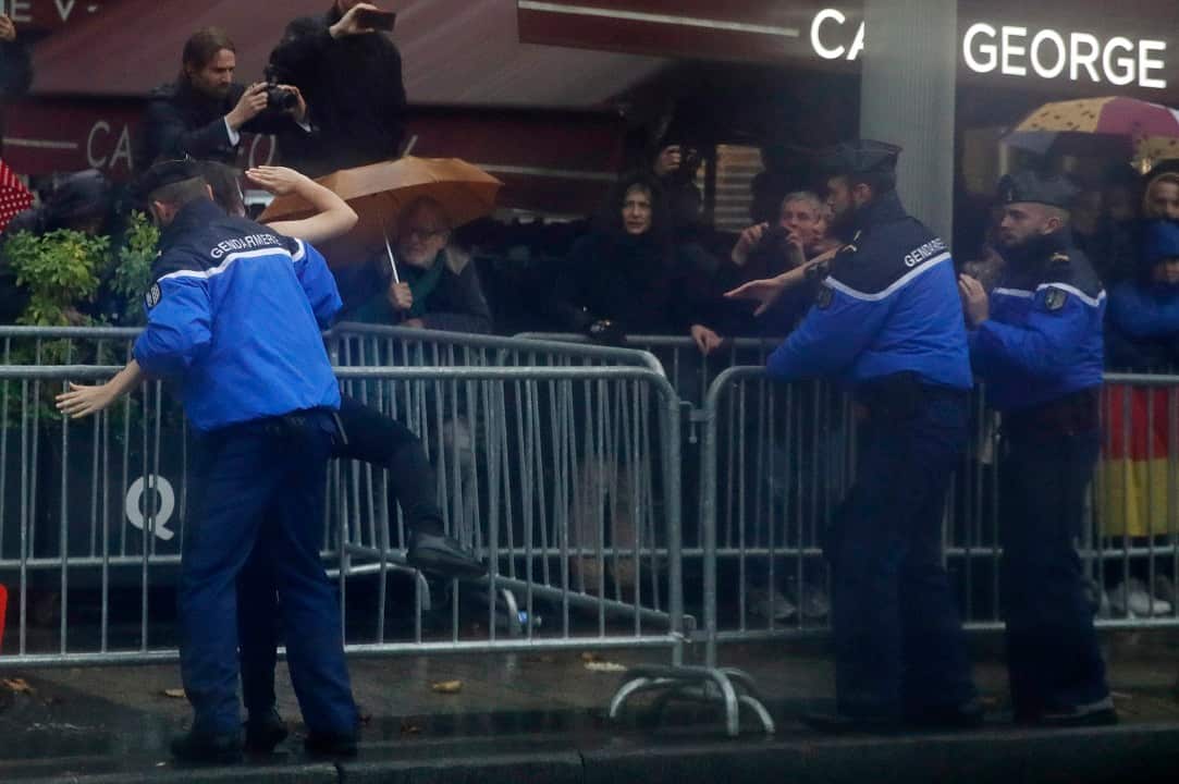 French police officers apprehend a topless protestr who ran toward the motorcade of President Donald Trump.