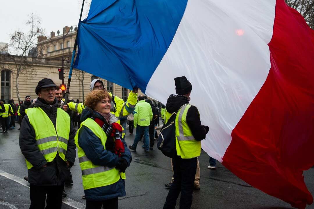 People stand in front of the French flag during the 10th act of the yellow vests demonstration in Paris on January 19, 2019. Photo by Julie Sebadelha/ABACAPRESS.COM.