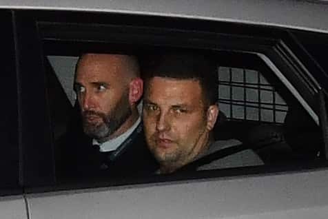 Zlatko Sikorsky (right) in a police car arriving at Maroochydore Police Station after the 28-hour siege. 