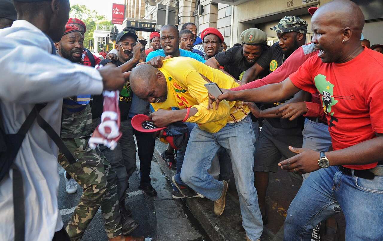 Protesting supporters of the opposition Economic Freedom Fighters (EFF) attack a member of the ruling party African National Congress (ANC)